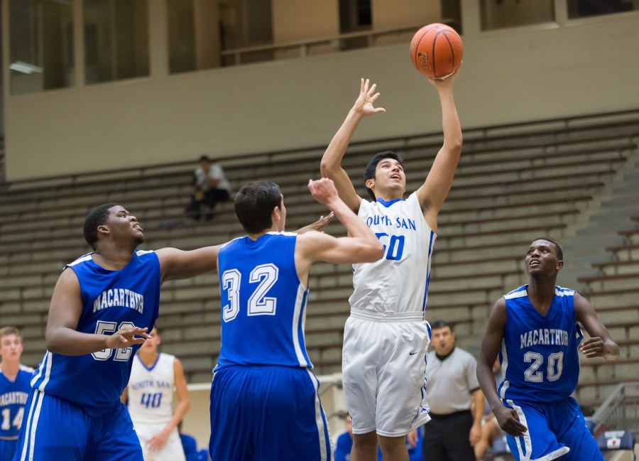 Bobcats junior Andre Flores clears a rebound against MacArthur's front line.
